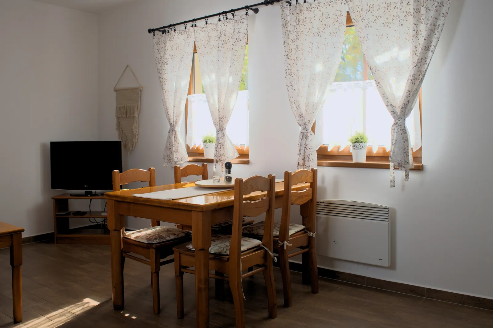 Jídelní stůl a obývací část Apartmánu 1 u oken do zahrady