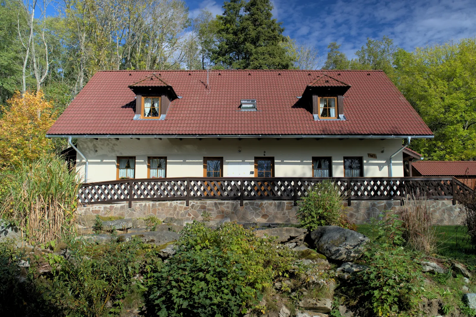 Průčelí domu s terasou a skalkou